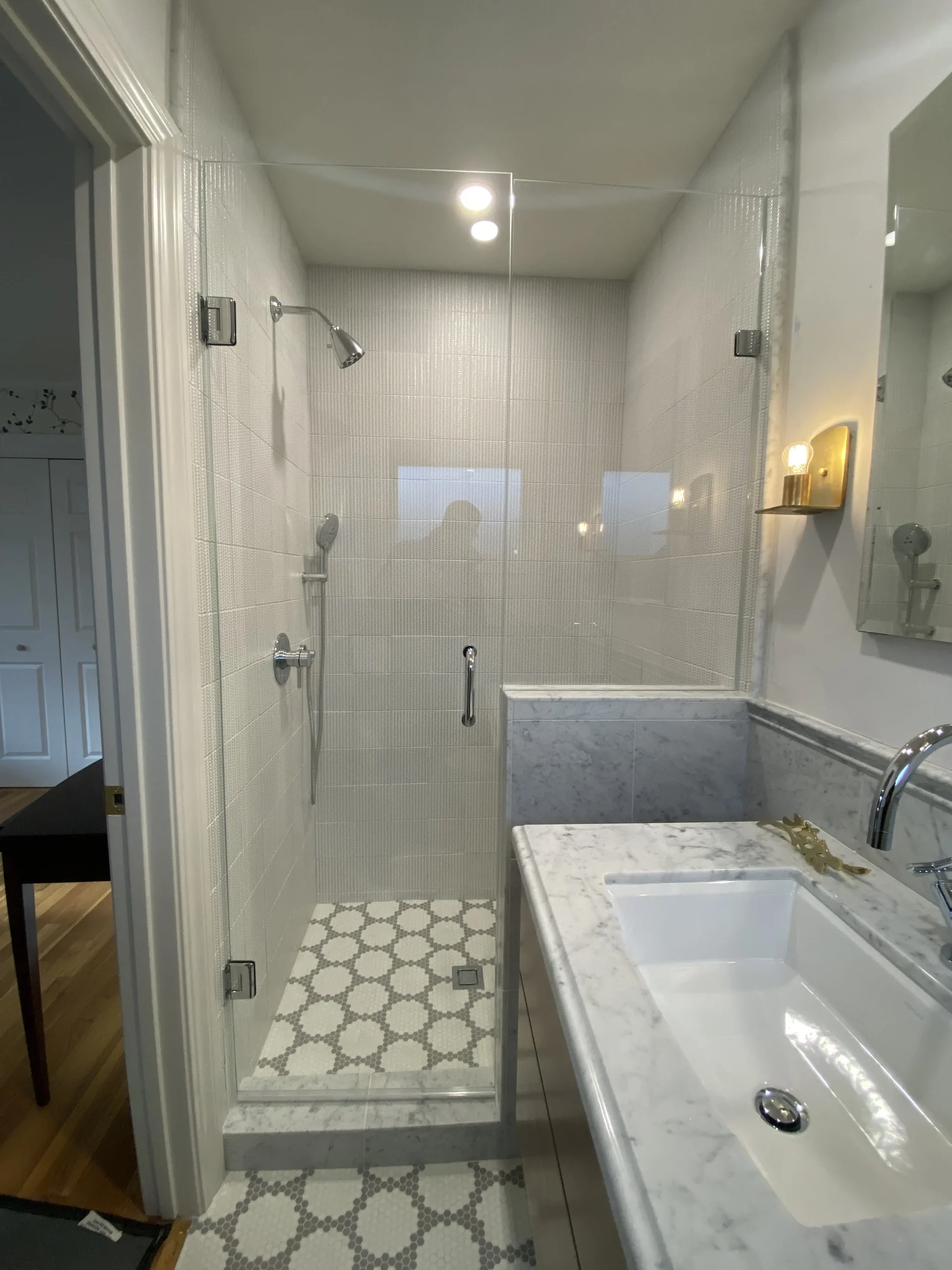 Modern bathroom featuring a glass shower enclosure, marble countertops, and tile flooring