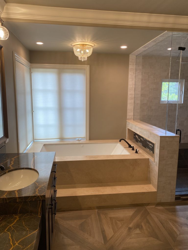 Finished master bathroom with a drop-in soaking tub beneath a window and a glass shower enclosure